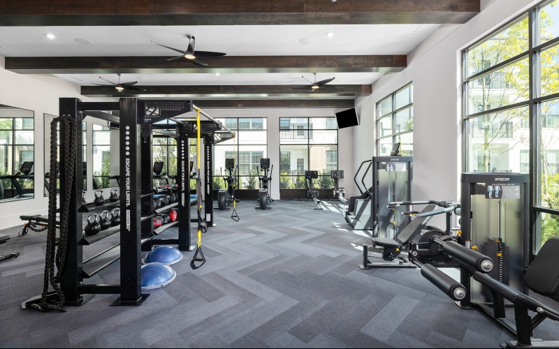 Room with gym equipment, large windows, and ceiling fans 