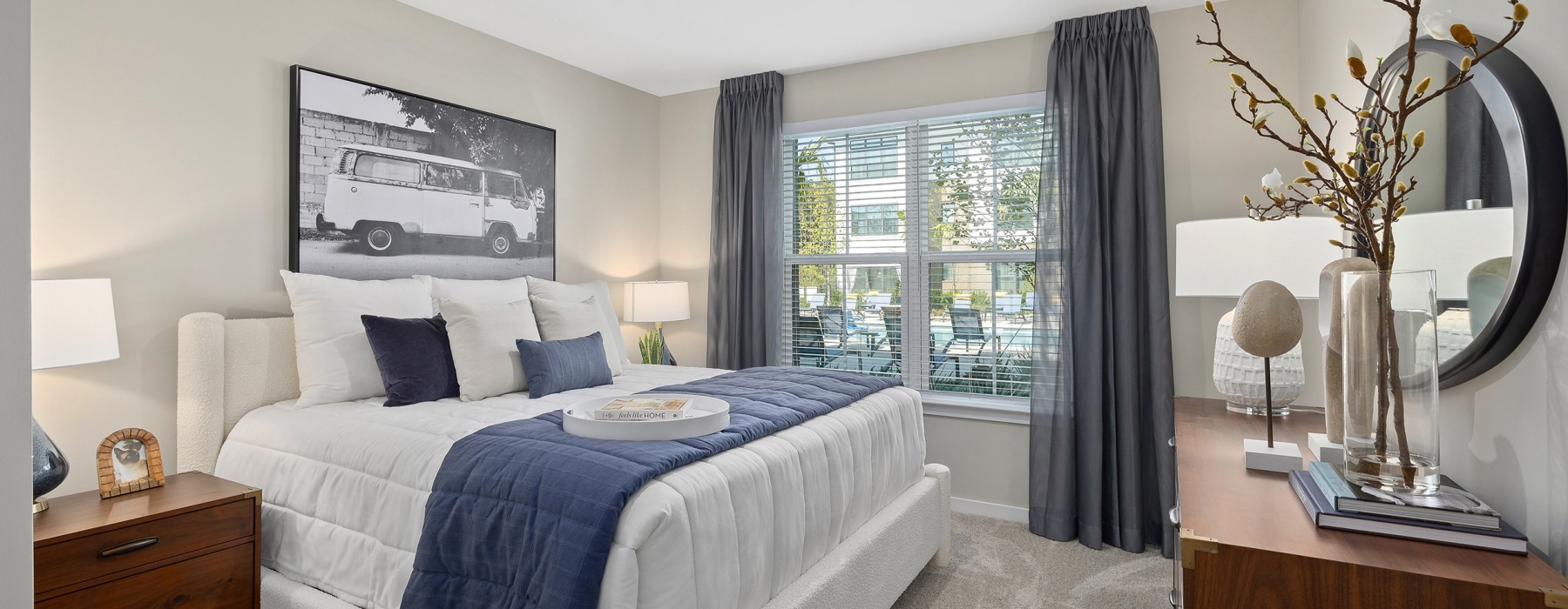 Bedroom with large bed, lamps, end tables, and a picture on the wall. 